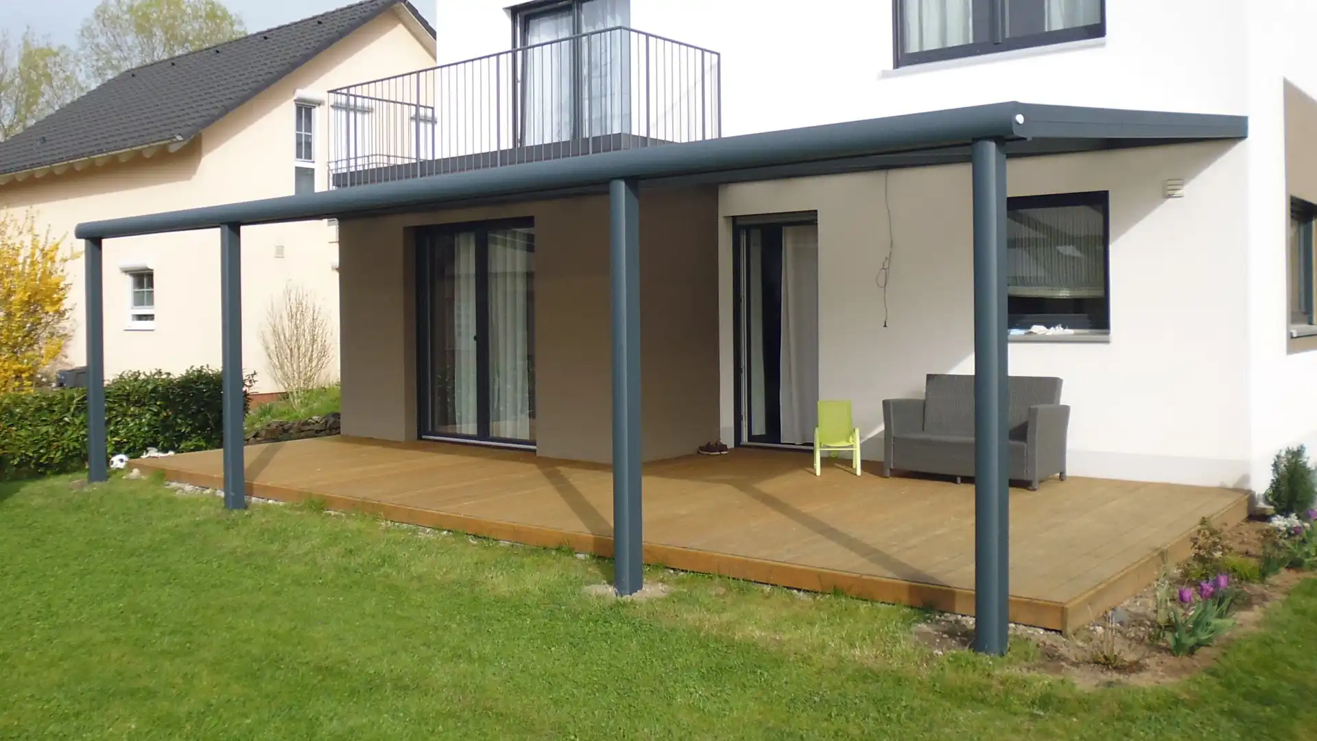 Terrassendach aus Aluminium mit Glaseindeckung und zwei Pfosten an einem Wohnhaus