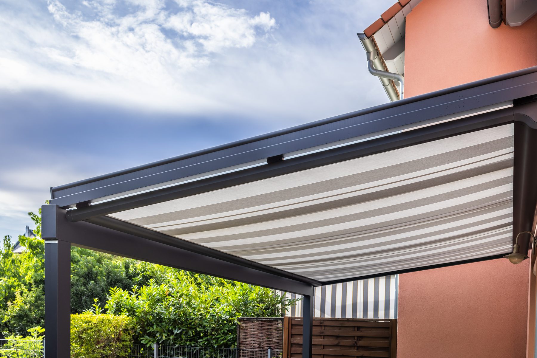 Terrassendach aus Aluminium mit darüber liegender Aufdachmarkise über einer Terrasse